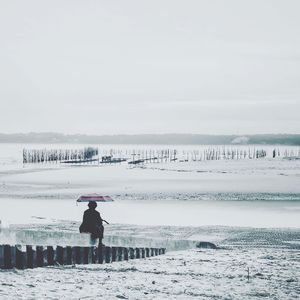 Woman standing on beach during winter against sky