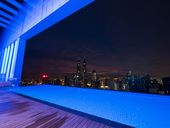 Illuminated city against blue sky at night