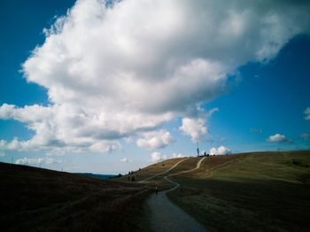 Empty road amidst field against sky