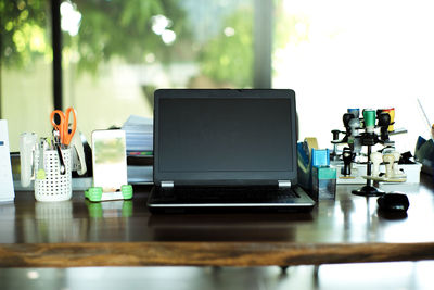 Work from home concept. closeup laptop on the wooden table surrounded by the office stationaries