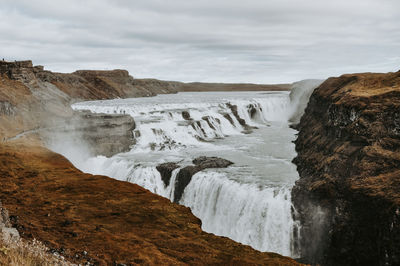 Scenic view of waterfall against sky