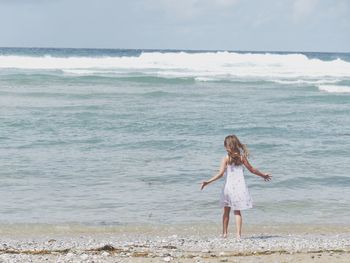 Rear view of girl standing at beach