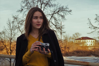 Beautiful woman looking away while holding camera