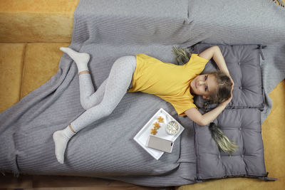 Directly above shot of girl relaxing on sofa at home