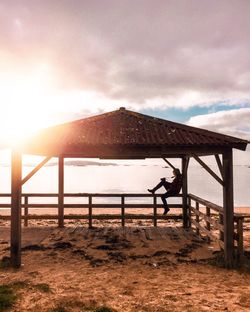 Gazebo on beach against sky during sunset