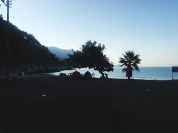 Silhouette palm trees on beach against clear sky