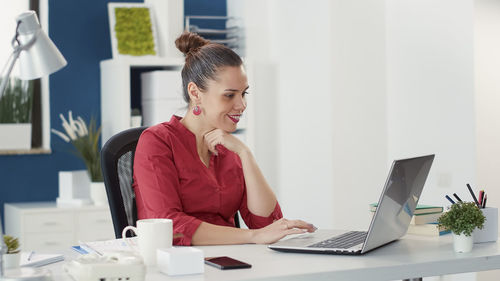 Smiling businesswoman using laptop at desk