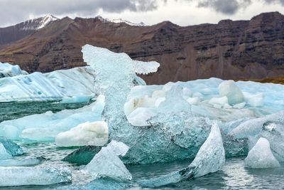 Icebergs in sea against mountains during winter