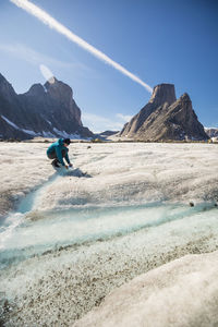 Mountaineer fills up water bottle from a glacial river, akshayak pass.