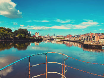 Scenic view of river by buildings against blue sky