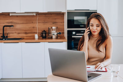 Portrait of smiling woman using smart phone at home