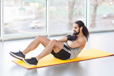 Side view of man sitting on window