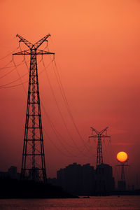 Silhouette electricity pylon against sky during sunset