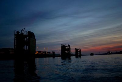 Silhouette men by sea against sky during sunset