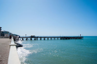 Pier over sea against clear blue sky