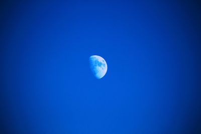 Low angle view of moon against blue sky