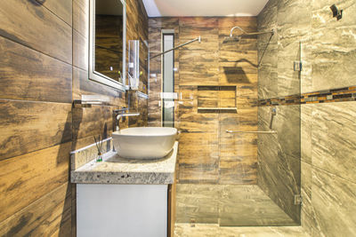 Bathroom with luxury finishes, main mirror with led light from behind, white ceramic washbasin