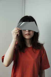 Close-up of woman holding glass against gray background