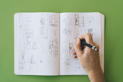 Architect drawing sketches on notebook on green table