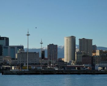 Sea by buildings against clear blue sky