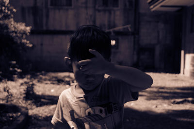 Rear view of boy standing against building
