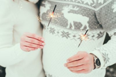 Midsection of couple holding sparklers