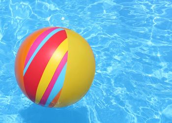 Close-up of multi colored ball floating on swimming pool