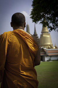 Rear view of monk standing outside buddhist temple