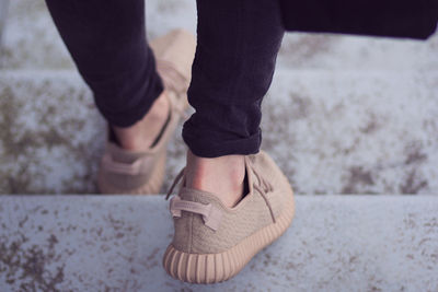 Low section of man wearing shoes while moving down on staircase