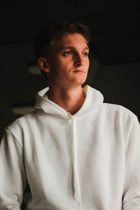 Portrait of young man standing against black background