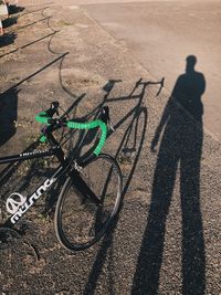 Shadow of man with bicycle on road