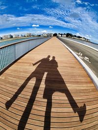 Shadow of people on railing by sea against sky