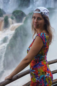 Smiling woman looking away against waterfall