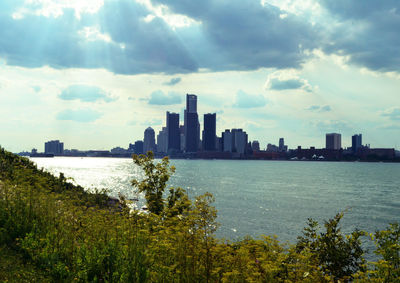 Sea by city buildings against sky