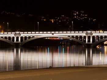 Illuminated bridge in city at night