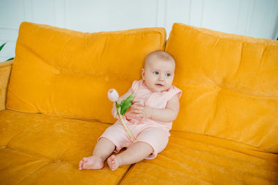 Child on a yellow sofa with flowers at home