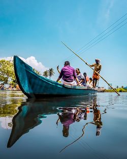 Reflection of people on boat in lake against sky