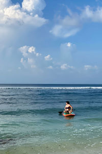 Young woman kayaking in sea against sky