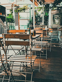 Empty chairs and tables at sidewalk cafe against building