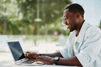 Side view of man using laptop at park