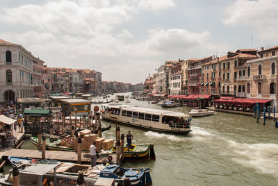 Boats moored in canal amidst buildings in city against sky