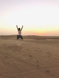 Woman relaxing on sand at beach against sky