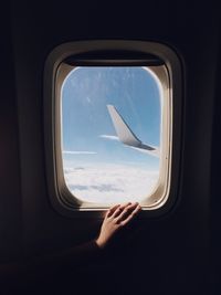 Cropped hand of person on window traveling in airplane