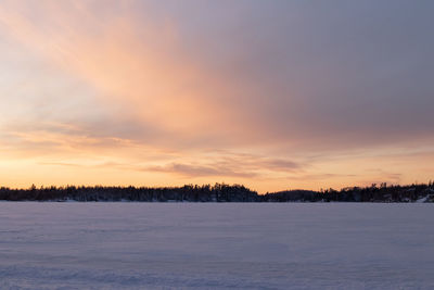 Scenic view of snow covered landscape against sky at sunset