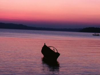 Silhouette boat in sea against sky during sunset