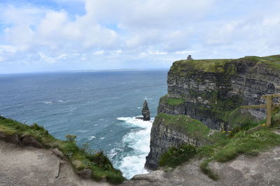 Scenic view of sea by cliff against sky