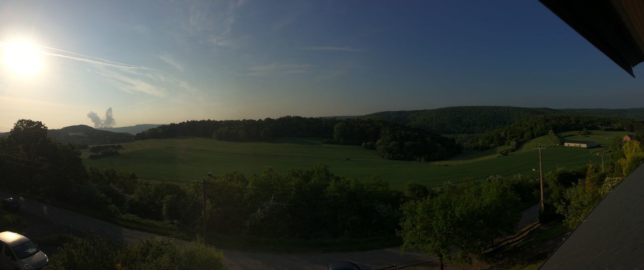 mountain, landscape, sky, scenics, tranquil scene, tranquility, sunlight, beauty in nature, blue, nature, road, mountain range, sunbeam, tree, panoramic, lens flare, non-urban scene, high angle view, hill, outdoors