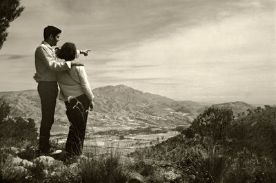 Rear view of friends standing on mountain against sky