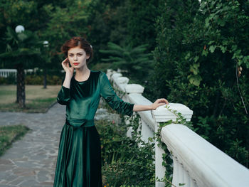 Portrait of young woman standing against plants