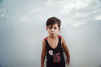 Portrait of boy standing against wall